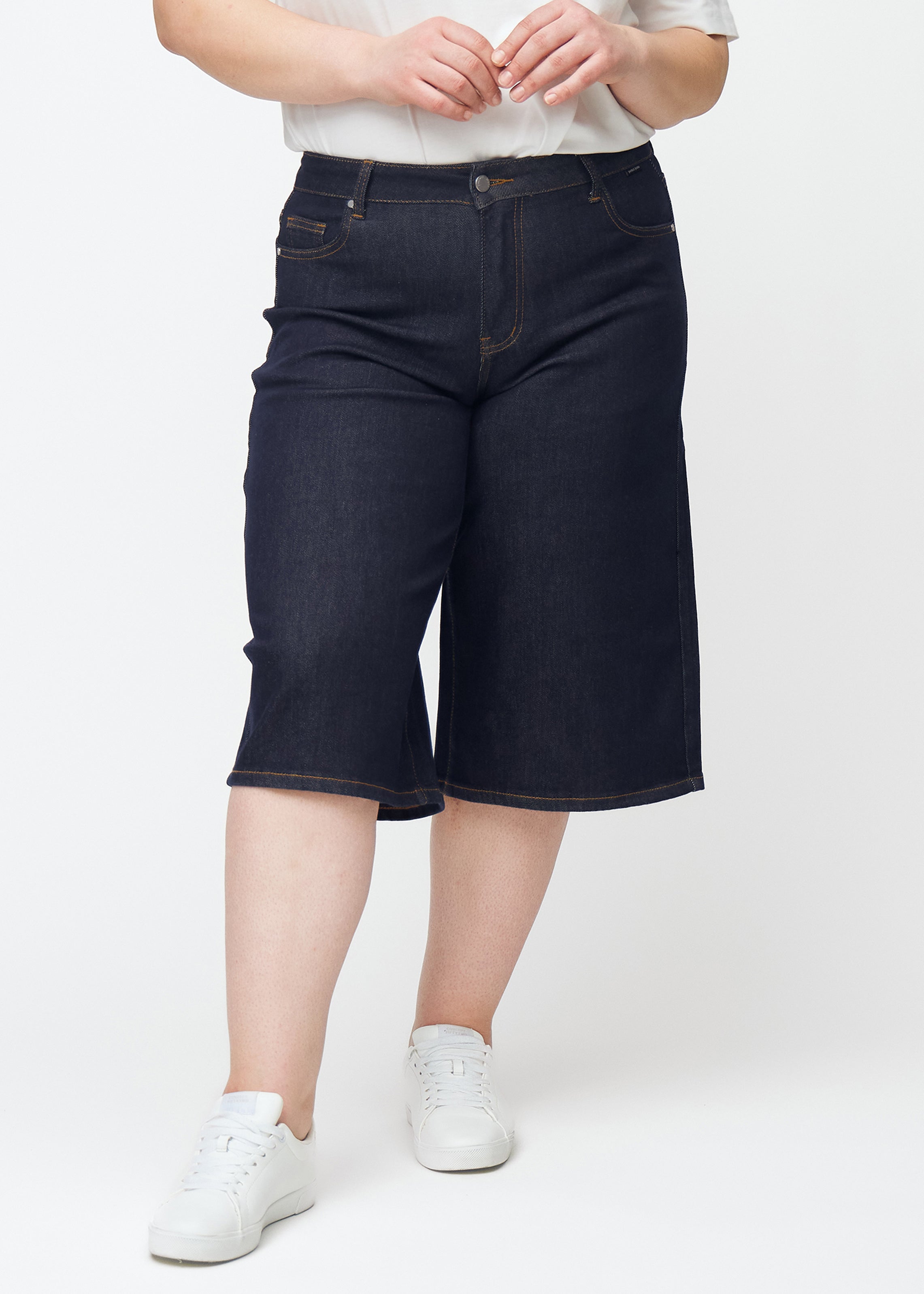 Dyp mørkeblå denim capris til dame i fargen Midnights med loose passform sett forfra på plus-size modell.