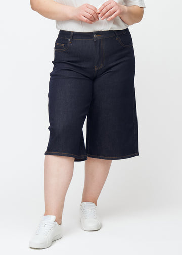 Dyp mørkeblå denim capris til dame i fargen Midnights med loose passform sett forfra på plus-size modell.