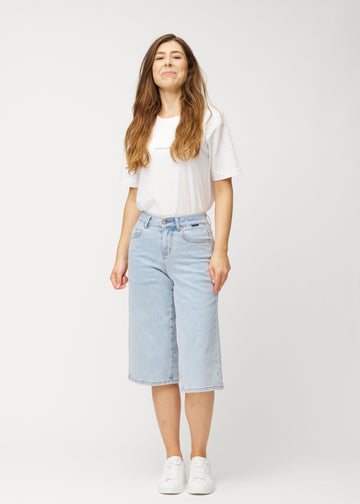 Helbilde av en modell i løse, lyseblå Waves denimcapribukser som slutter rett under kneet.