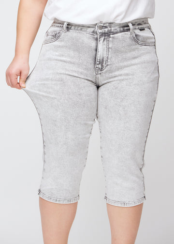 Plus-size-modellen strekker caprisene ved låret for å vise stretch.