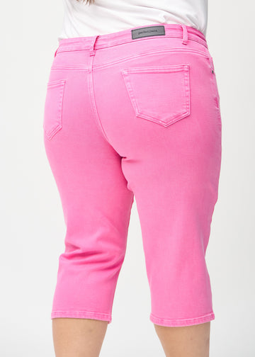 Lyserosa regular capris sett bakfra på nært hold på en plus-size-modell for å vise detaljer.
