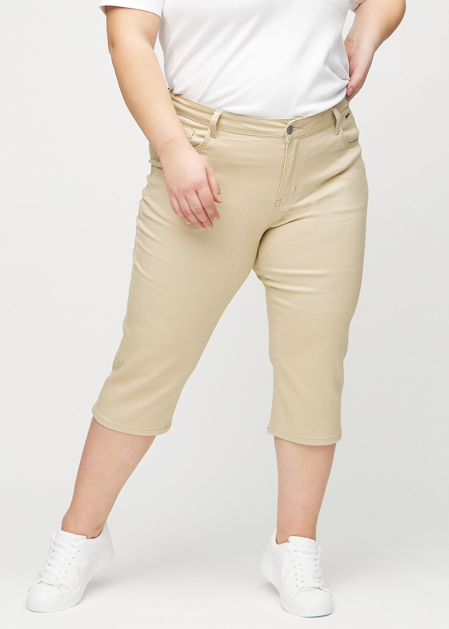 Beige regular capris, modellnavn Gazelles, som sitter tett langs benet og slutter rett under kneet på en plus-size-modell, sett forfra.