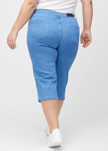 Blå regular capris sett bakfra på en plus-size-modell, så man kan se hele produktet.