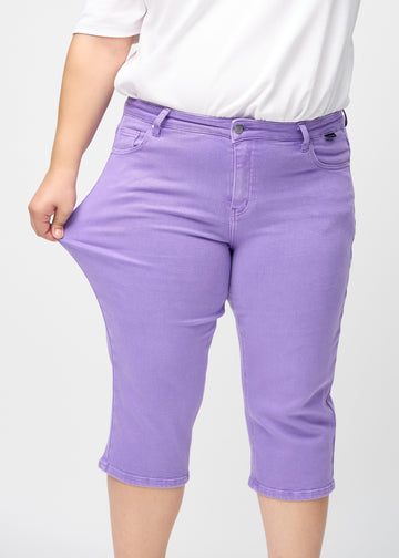 Plus-size-modellen strekker caprisene ved låret for å vise stretch.