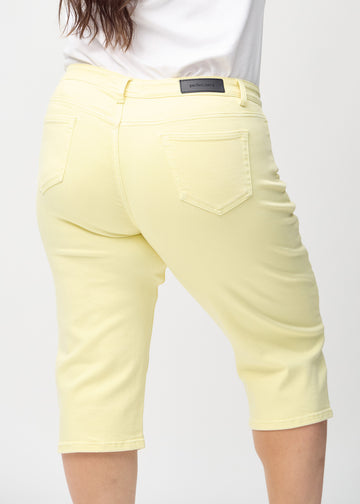 Lysegule regular capris sett bakfra på nært hold på en plus-size-modell for å vise detaljer.