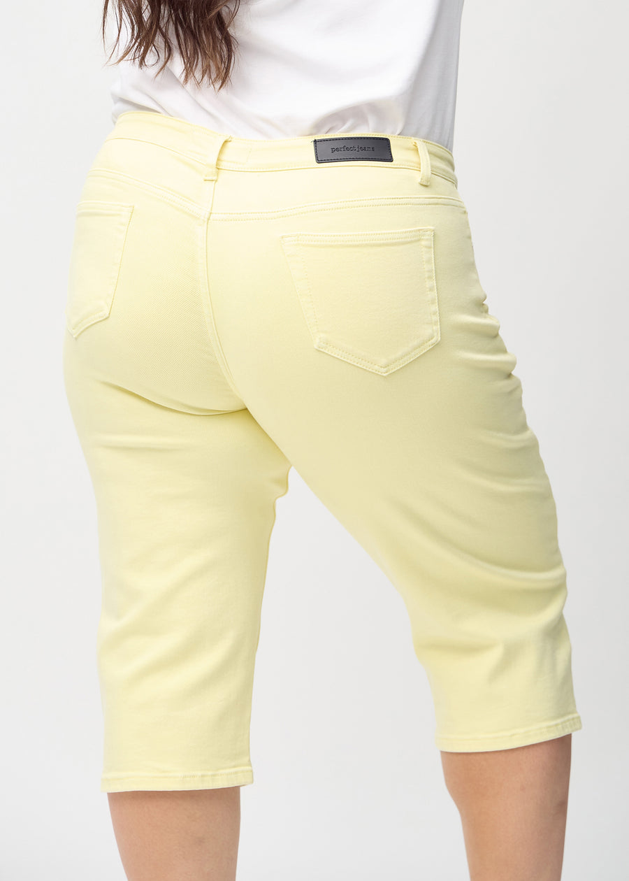Lysegule regular capris sett bakfra på nært hold på en plus-size-modell for å vise detaljer.