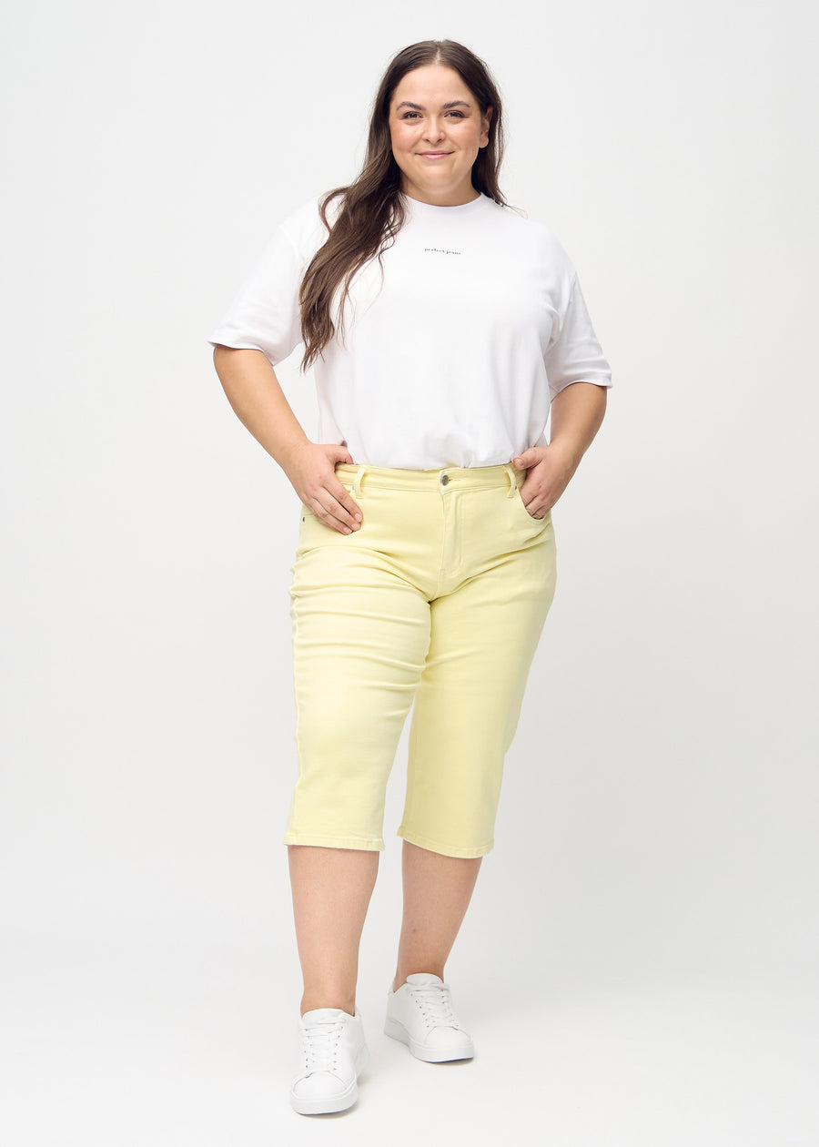 Lysegule regular capris sett bakfra på nært hold på en plus-size-modell for å vise detaljer.