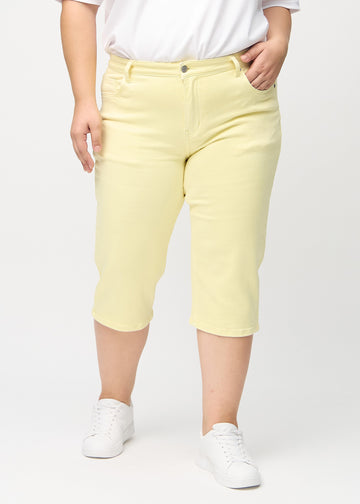 Lysegule regular capris, modellnavn Lemonades, som går rett ned langs benet på en plus-size-modell, sett forfra.