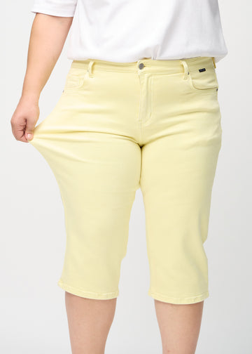 Plus-size-modellen strekker caprisene ved låret for å vise stretch.
