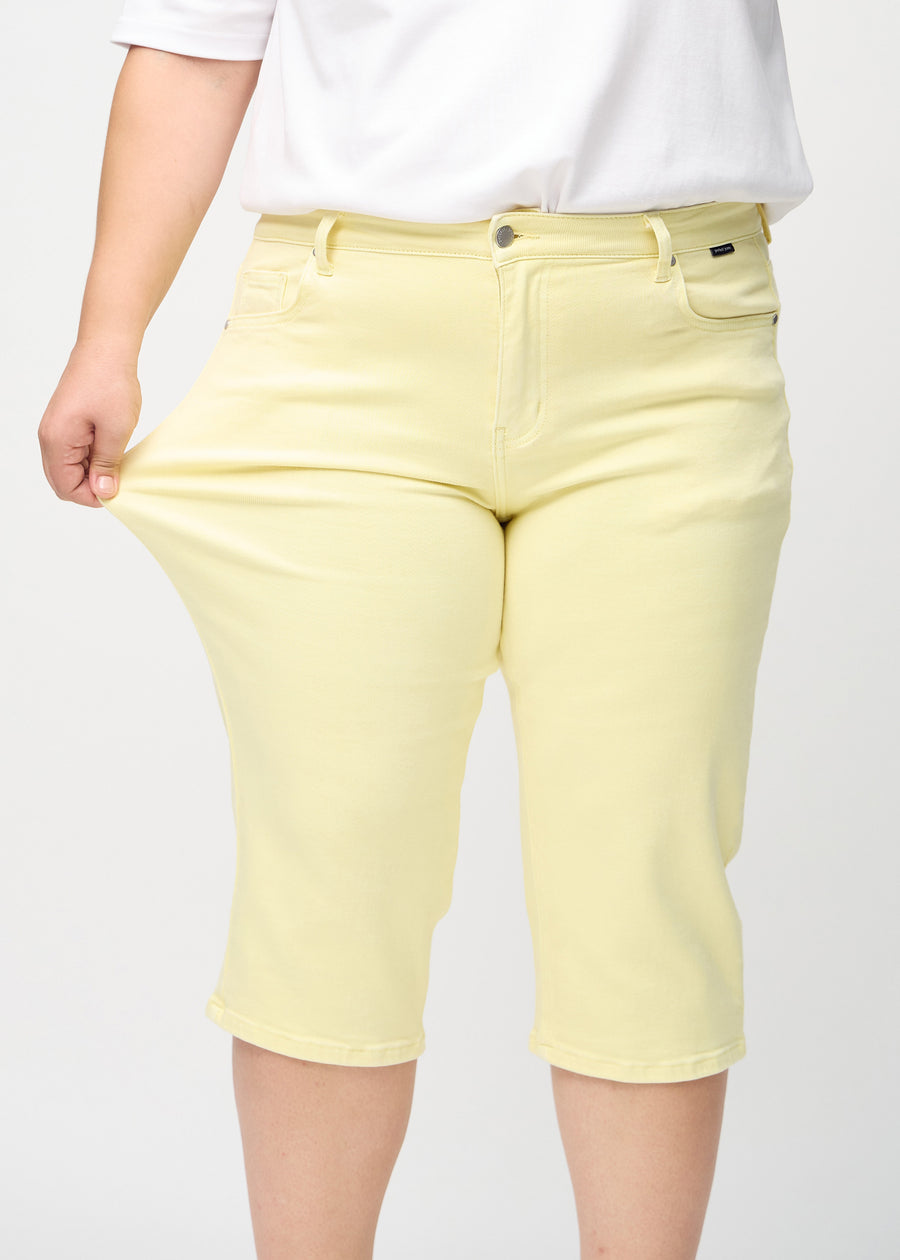 Plus-size-modellen strekker caprisene ved låret for å vise stretch.
