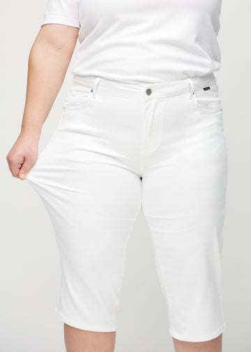 Plus-size-modellen strekker caprisene ved låret for å vise stretch.