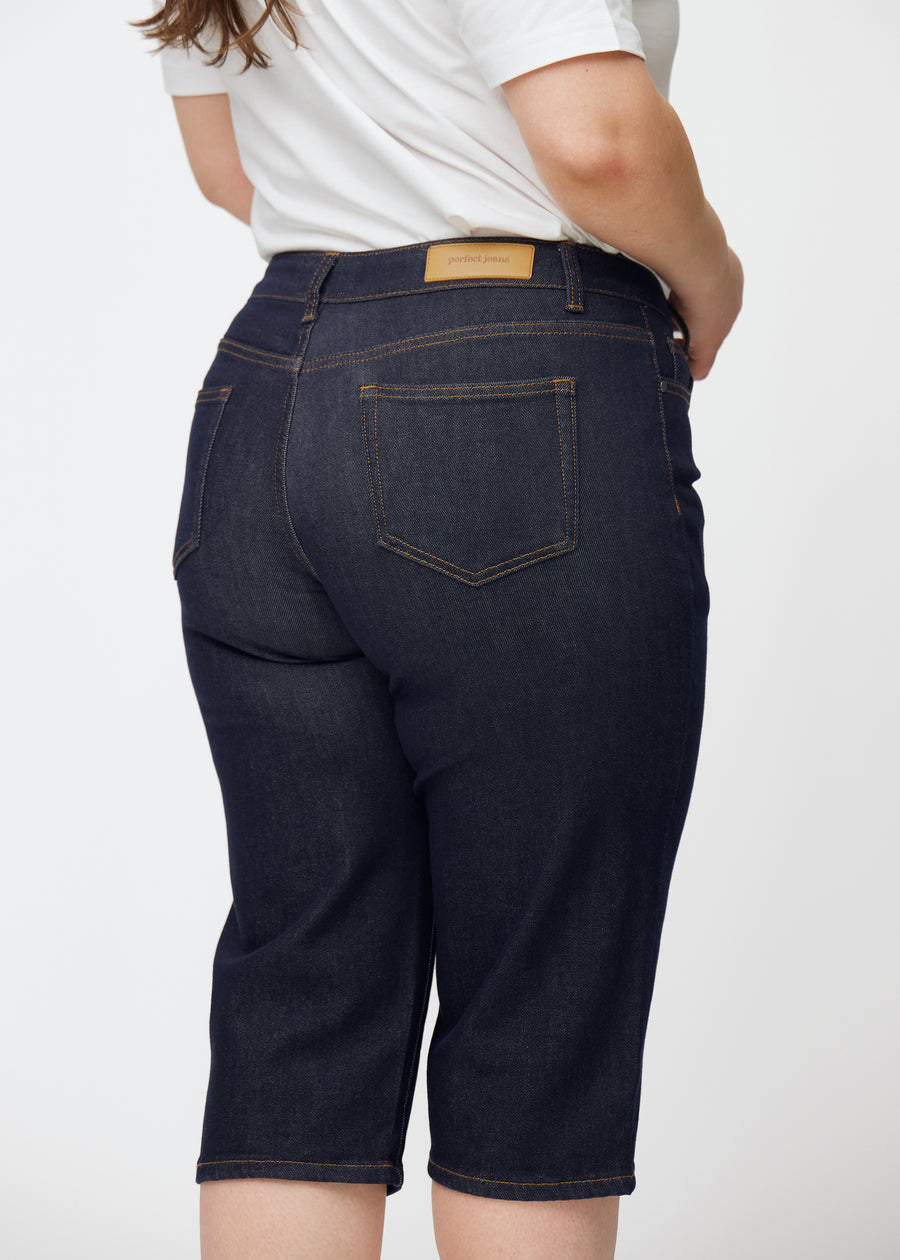 Dyp mørkeblå denim capris til dame i fargen Midnights sett bakfra i nærbilde på plus-size modell.
