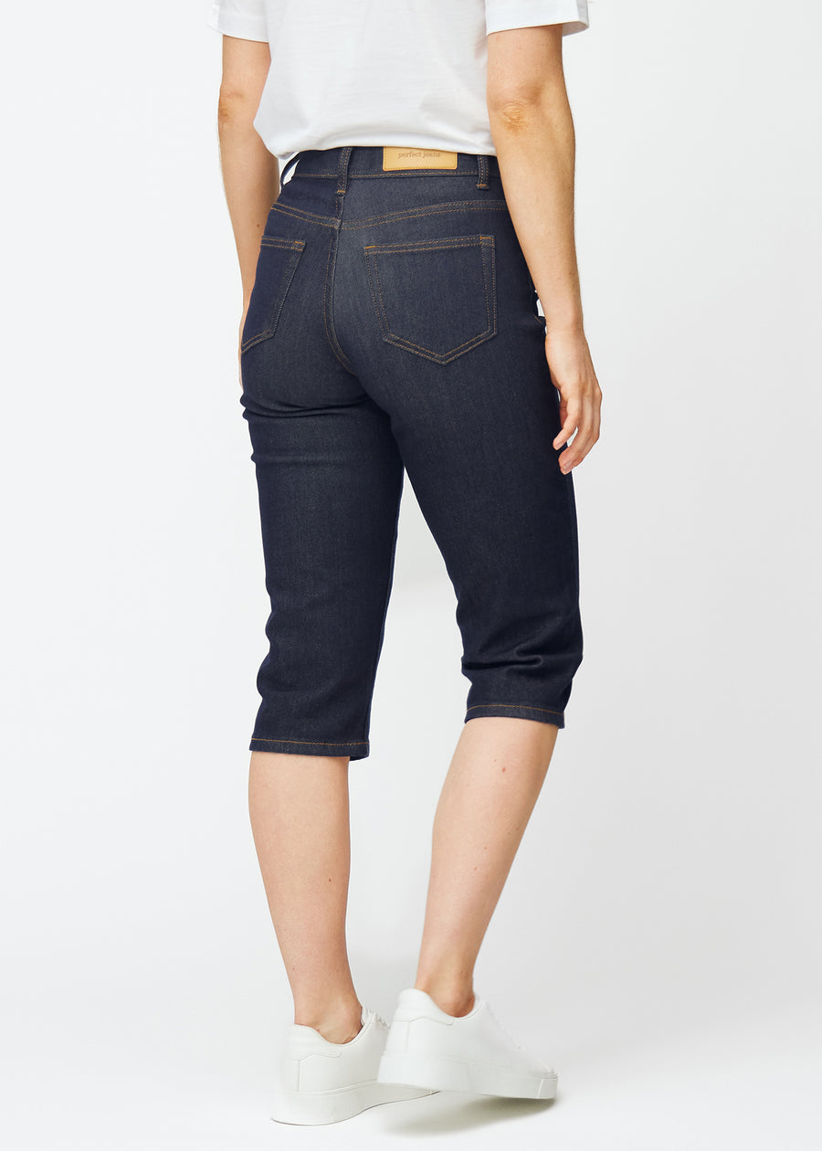 Dyp mørkeblå denim capris til dame i fargen Midnights sett bakfra, slik at lengden under kneet vises.