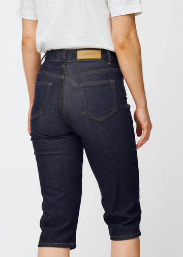 Dyp mørkeblå denim capris til dame i fargen Midnights sett bakfra i nærbilde for å vise passform og detaljer.