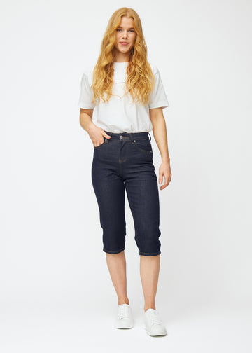 Helbilde av modell i dyp mørkeblå denim capris til dame i fargen Midnights med regular passform.
