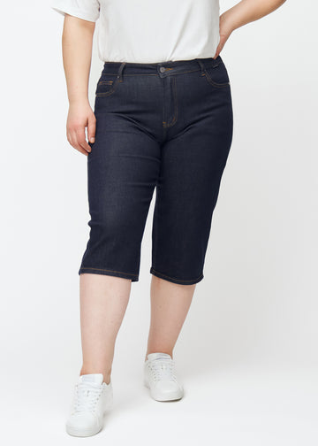 Dyp mørkeblå denim capris til dame i fargen Midnights med regular passform sett forfra på plus-size modell.