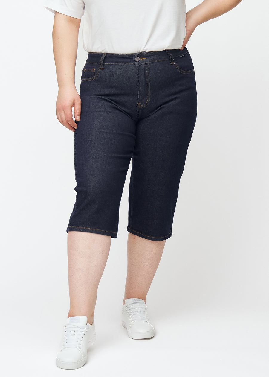 Dyp mørkeblå denim capris til dame i fargen Midnights med regular passform sett forfra på plus-size modell.