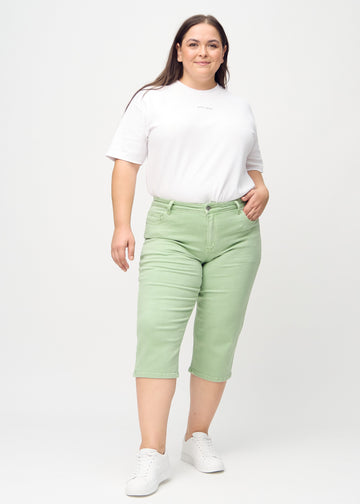 Fullt bilde av en plus-size-modell i lysegrønne regular capris.