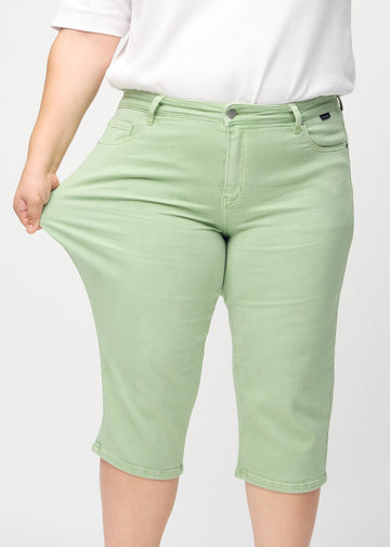 Plus-size-modellen strekker caprisene ved låret for å vise stretch.