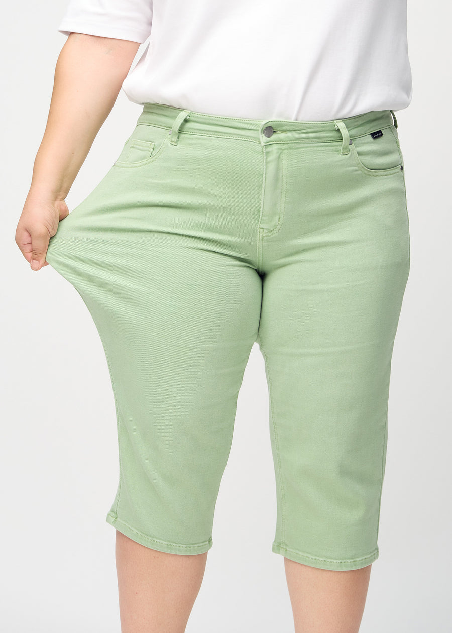 Plus-size-modellen strekker caprisene ved låret for å vise stretch.