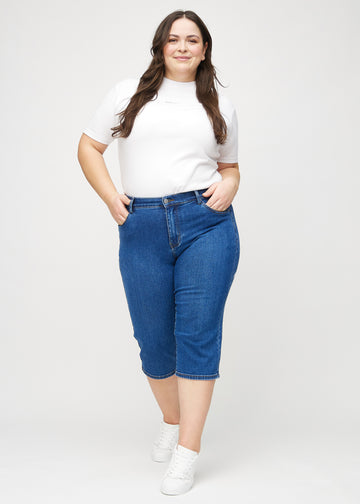 Fullt bilde av en plus-size modell i mørk denim regular capris.