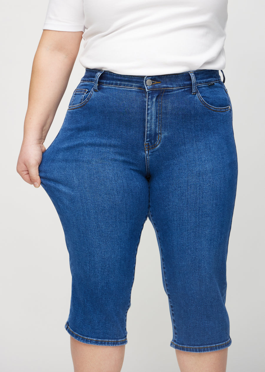 Plus-size modell strekker caprisene ved låret for å vise stretch.