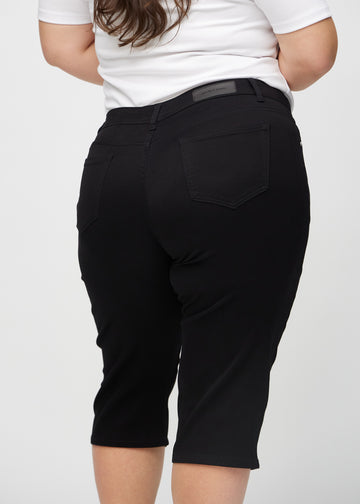 Svarte regular capris sett bakfra på nært hold på en plus-size modell for å vise detaljer.