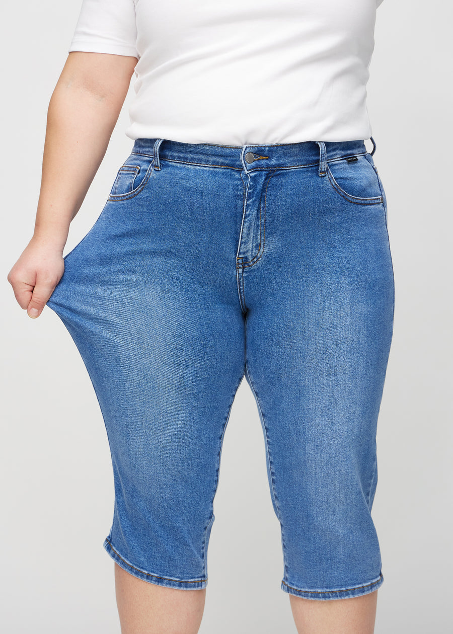 Plus-size-modellen strekker caprisene ved låret for å vise stretch.