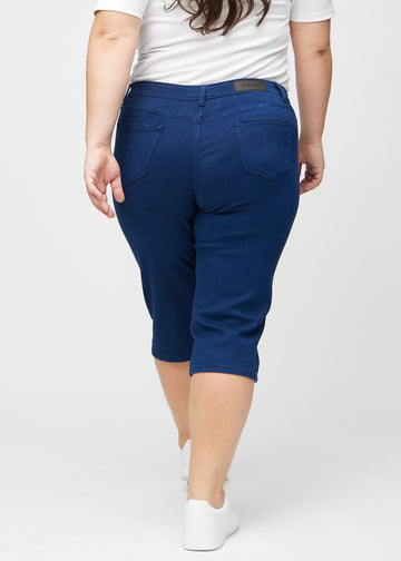 Mørkeblå regular capris sett bakfra på en plus-size-modell, slik at man kan se hele produktet.