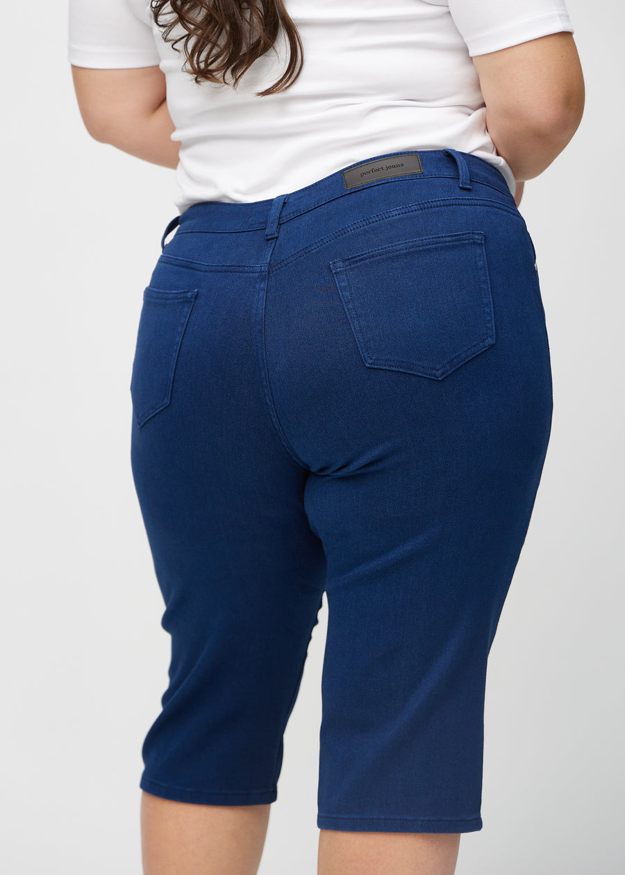 Mørkeblå regular capris sett bakfra på nært hold på en plus-size-modell for å vise detaljer.