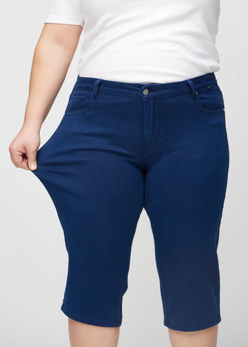 Plus-size-modellen strekker caprisene ved låret for å vise stretch.