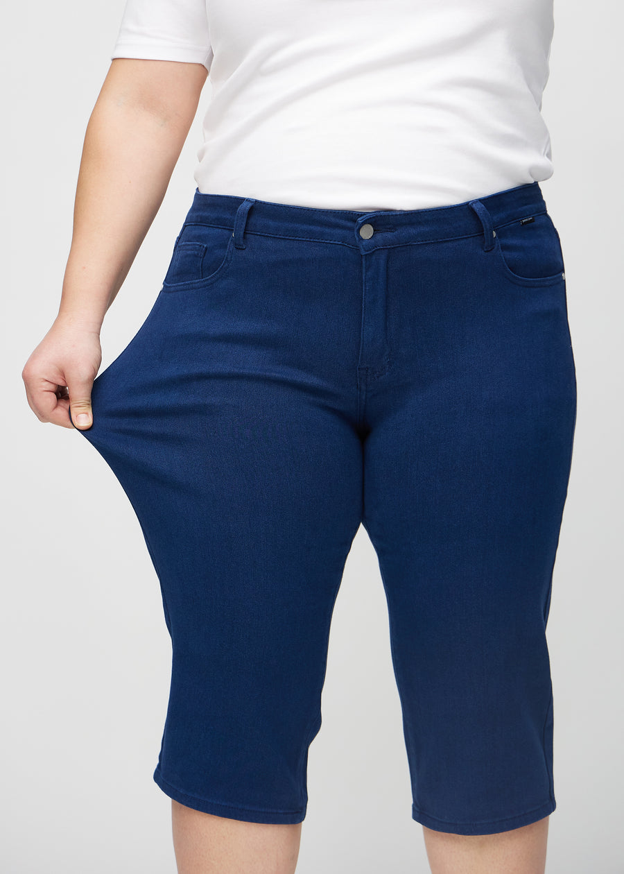 Plus-size-modellen strekker caprisene ved låret for å vise stretch.