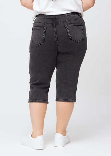 Mørkegrå denim regular capris sett bakfra på en plus-size-modell, slik at man kan se hele produktet.