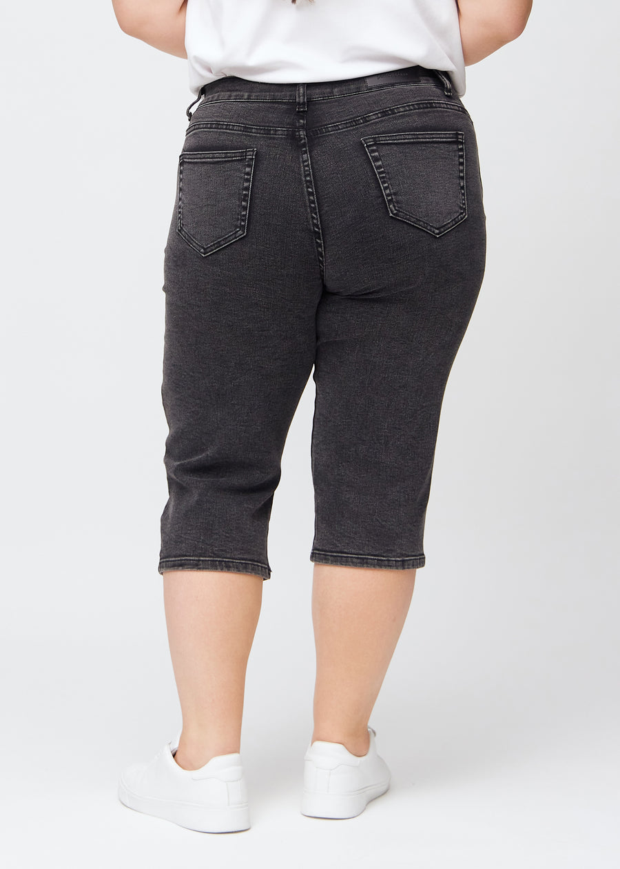 Mørkegrå denim regular capris sett bakfra på en plus-size-modell, slik at man kan se hele produktet.