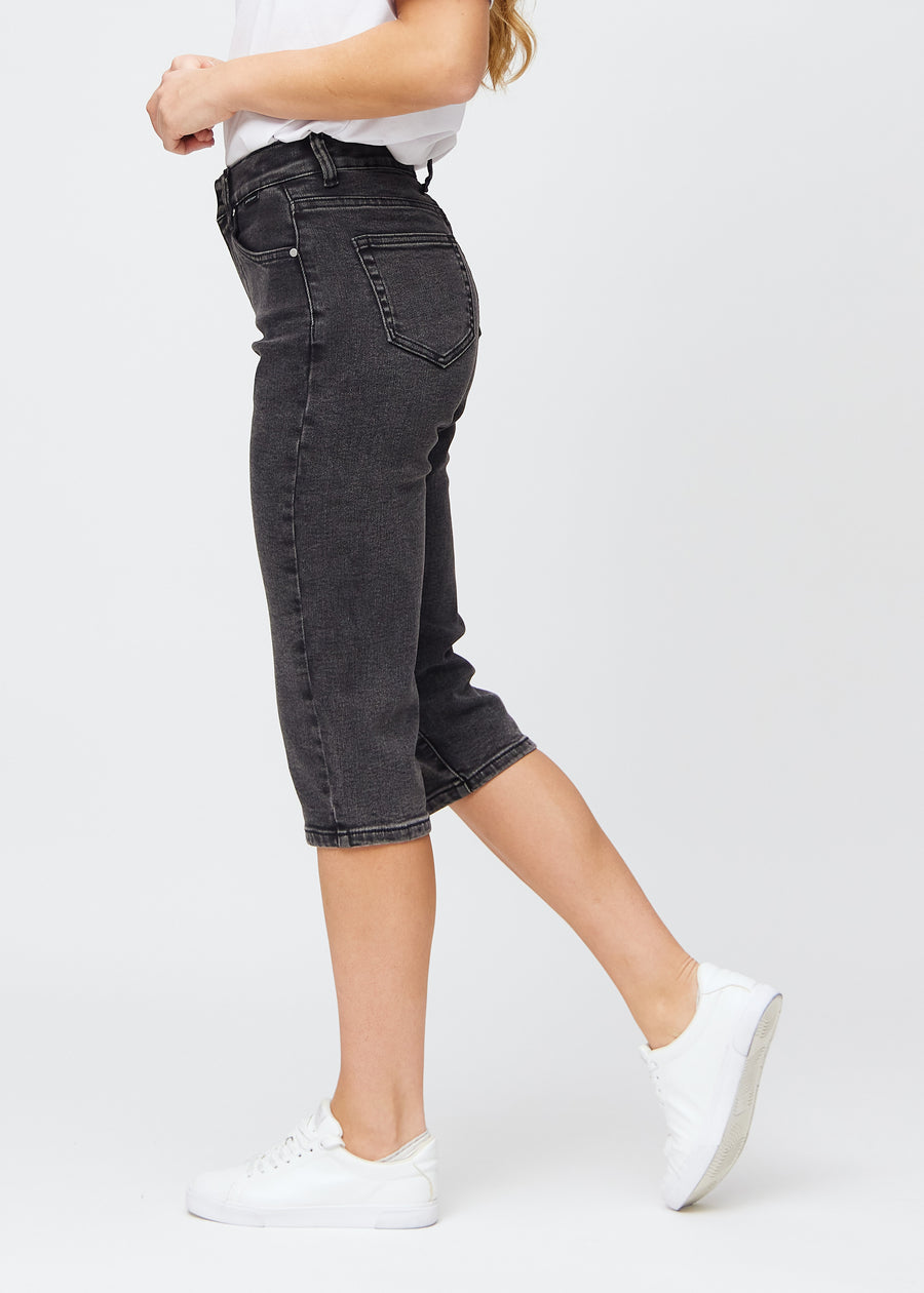 Mørkegrå denim regular capris sett fra siden på modell.
