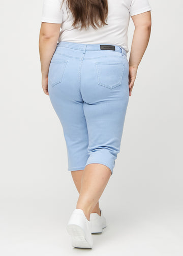 Lyseblå regular capris sett bakfra på en plus-size-modell, slik at man kan se hele produktet.