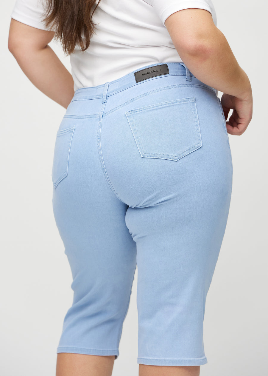 Lyseblå regular capris sett bakfra på nært hold på en plus-size-modell for å vise detaljer.