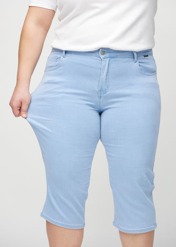 Plus-size-modellen strekker caprisene ved låret for å vise stretch.