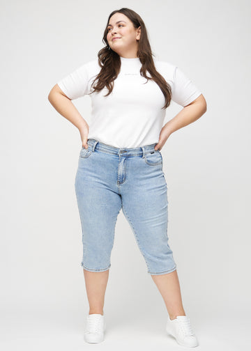 Fullt bilde av en plus-size-modell i lys denim regular capris.