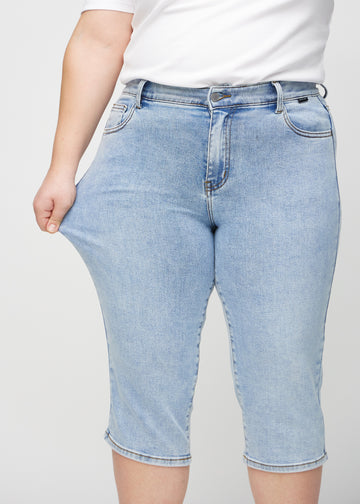 Plus-size-modellen strekker caprisene ved låret for å vise stretch.