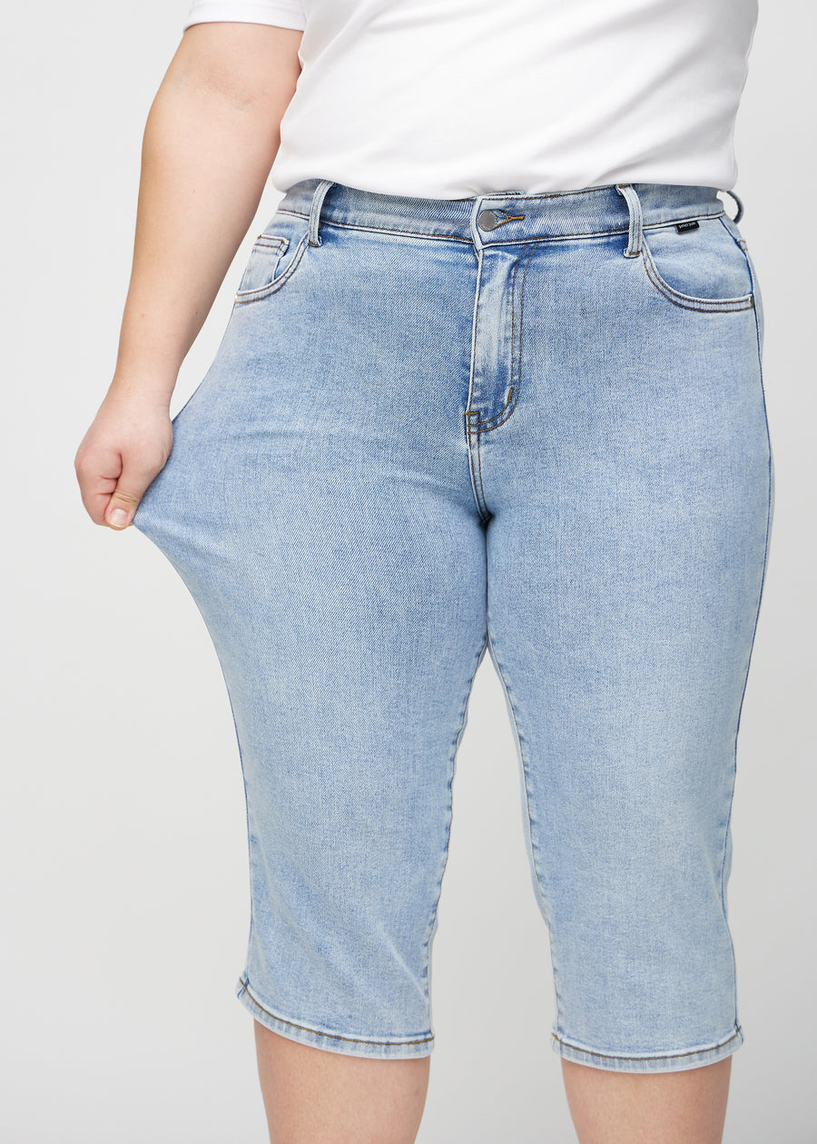 Plus-size-modellen strekker caprisene ved låret for å vise stretch.