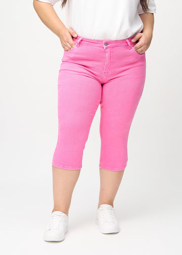 Skinny-capris til kvinner i pastellrosa jeansstoff, fargen Flamingos. Sett forfra på en plus size-modell, med tettsittende ben til rett under kneet.