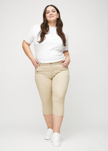 Skinny-capris til kvinner i beige jeansstoff, fargen Gazelles. Helhetsbilde av en plus size-modell med capris på.