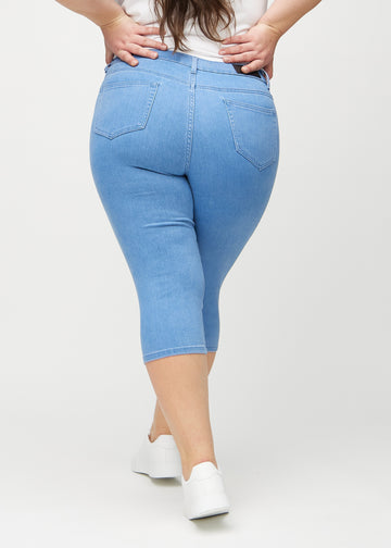 Skinny-capris til kvinner i blått jeansstoff, fargen Geraniums. Sett bakfra på en plus size-modell, med fokus på passform og baklommer.