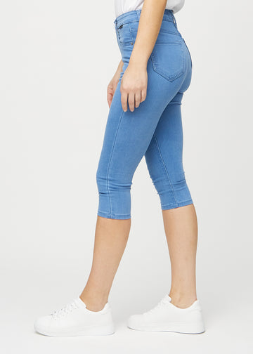 Skinny-capris til kvinner i blått jeansstoff, fargen Geraniums. Sett fra siden på en modell, med tettsittende passform.