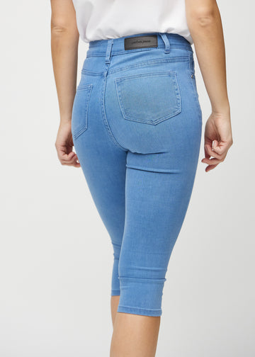 Skinny-capris til kvinner i blått jeansstoff, fargen Geraniums. Nærbilde bakfra på en modell, med fokus på lommer og sømmer.