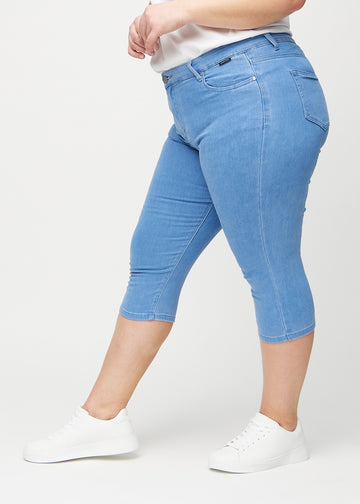 Skinny-capris til kvinner i blått jeansstoff, fargen Geraniums. Sett fra siden på en plus size-modell, med tettsittende passform.