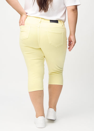 Skinny-capris til kvinner i pastellgult jeansstoff, fargen Lemonades. Sett bakfra på en plus size-modell, med fokus på passform og baklommer.