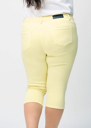Skinny-capris til kvinner i pastellgult jeansstoff, fargen Lemonades. Nærbilde bakfra på en plus size-modell, med fokus på lommer og sømmer.