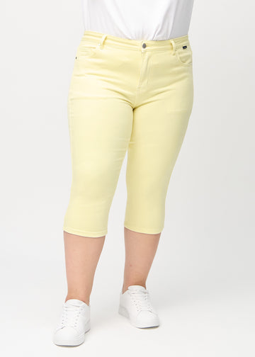 Skinny-capris til kvinner i pastellgult jeansstoff, fargen Lemonades. Sett forfra på en plus size-modell, med tettsittende ben til rett under kneet.